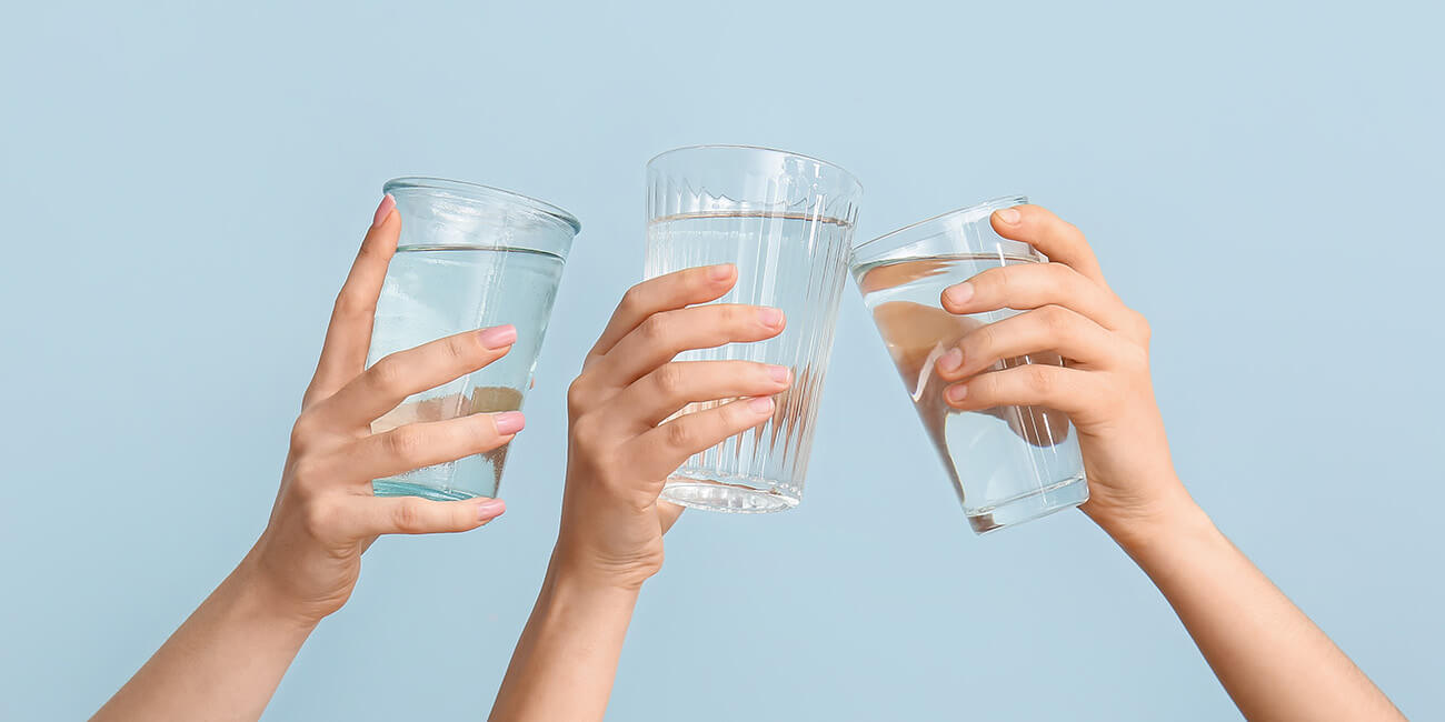 Three hands holding up glasses of water